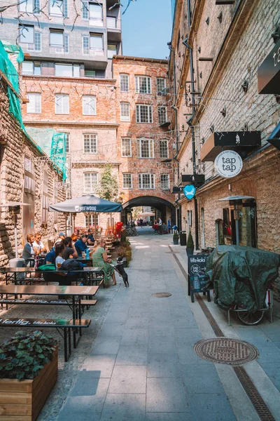 11 Haziran 2018. Tallinn Estonya sokaklarında açık sokak restoran. Rahat sandalyeler ve masalar bir tabloda bir şampanya şişesi ile eski şehir ayakta.