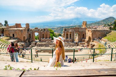 Jule 04, 2018. Taormina, İtalya. Güzel kız uzun beyaz elbise ve beyaz yaz şapka, antik Yunan tiyatro Taormina İtalya kazanı.