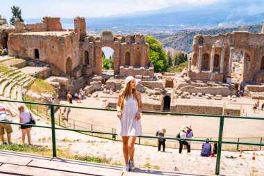Jule 04, 2018. Taormina, İtalya. Güzel kız uzun beyaz elbise ve beyaz yaz şapka, antik Yunan tiyatro Taormina İtalya kazanı.