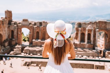 Jule 04, 2018. Taormina, İtalya. Güzel kız uzun beyaz elbise ve beyaz yaz şapka, antik Yunan tiyatro Taormina İtalya kazanı.