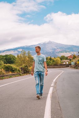 20 Mayıs 2010. Sicilya, İtalya. Ve patlama Etna Yanardağı yalnız yoldan görüntüleyin. Erüpsiyonu ile yolda arka planda yürüyen genç adam.