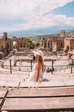 Jule 04, 2018. Taormina, İtalya. Güzel kız uzun beyaz elbise ve beyaz yaz şapka, antik Yunan tiyatro Taormina İtalya kazanı.