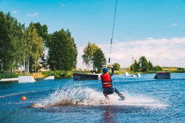Marupe, Letonya. 20 Temmuz 2018. Wakeboarding bir göl, raley yapma, frontroll ve atlama perlere ve kaydırıcıları genç adam. Wakeboard.