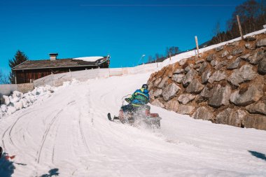 15 Mart 2018. Saalbach, Avusturya. Genç adam bir parça Avusturya Alplerinde ortasında bir kar arabası sürme.