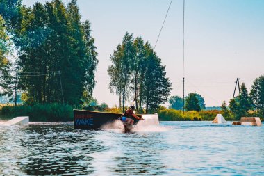 Marupe, Letonya. 20 Temmuz 2018. Wakeboarding bir göl, raley yapma, frontroll ve atlama perlere ve kaydırıcıları genç adam. Wakeboard. 