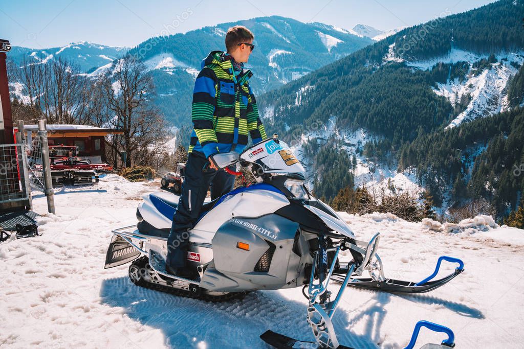 March 15, 2018. Saalbach, Austria. Young man riding a snowmobile on a track in the middle of the Austrian Alps.