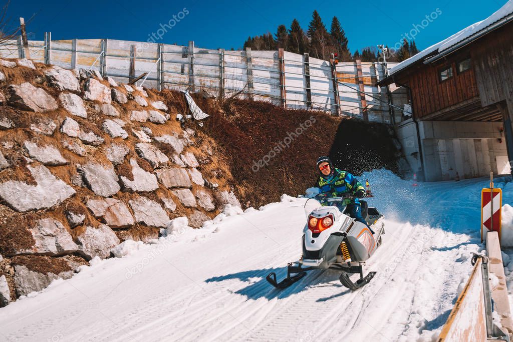 March 15, 2018. Saalbach, Austria. Young man riding a snowmobile on a track in the middle of the Austrian Alps.