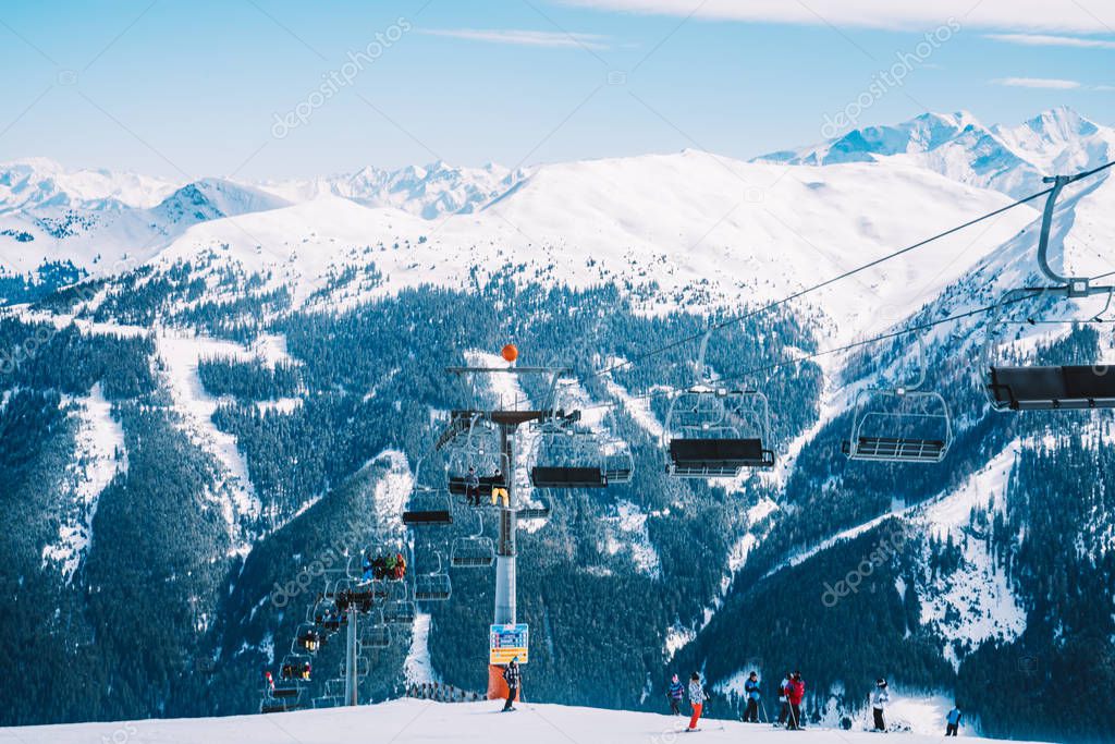 Ski lefts and cable cars in the Alps winter resort. People going up for skiing and snowboarding. Austrian Alps. 