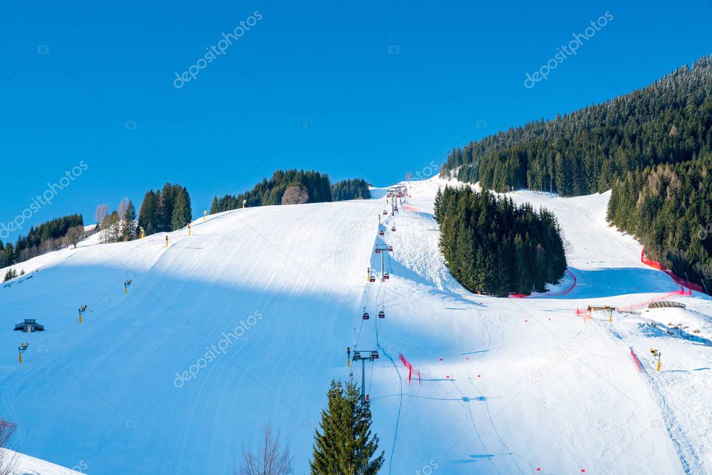 Ski lefts and cable cars in the Alps winter resort. People going up for skiing and snowboarding. Austrian Alps.