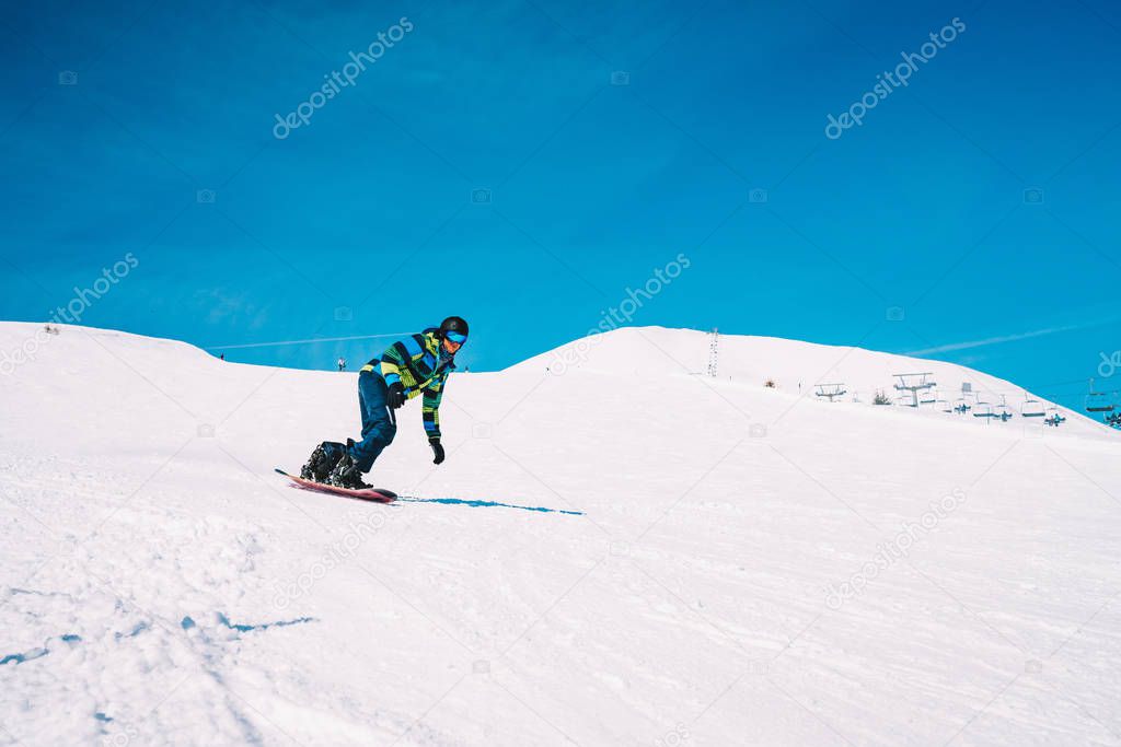 Snowboarder going down the slopes in Austrian Alps through forests, slopes and ski tracks. Skiing, snowboarding in the Alps.