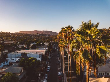 Palmiye ağaçları batımında Los Angeles'ta Hollywood yazısını ufukta ile Beverly Hills sokak.