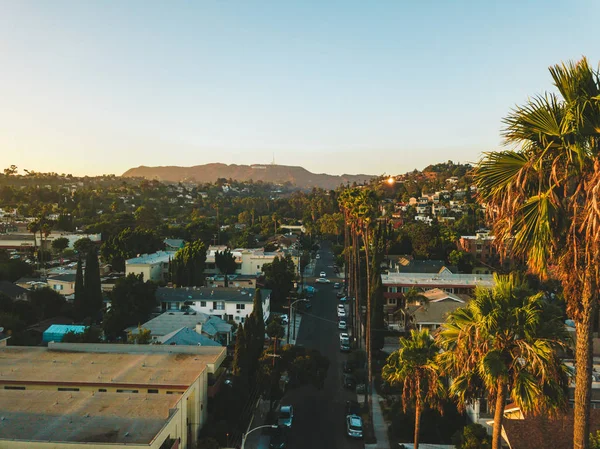 Palmiye ağaçları batımında Los Angeles'ta Hollywood yazısını ufukta ile Beverly Hills sokak.