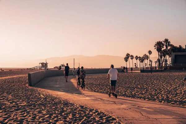 2018 ロサンゼルス アメリカ合衆国 ベニス ビーチ感じ つのホイールに乗っている人 自転車 スケート ボード ビーチとヤシの木をダウンします — ストック写真
