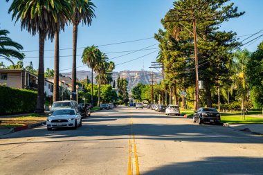 10 Haziran 2018. Los Angeles, Amerika Birleşik Devletleri. Beyaz Ford Mustang Gt Los Angeles'ta Hollywood sign tarafından sokakta park.