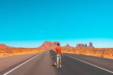 Monument Valley yolda yürüyen genç adam. 