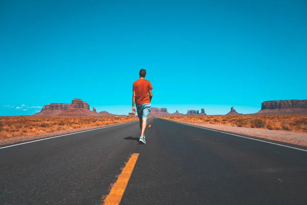 Young man walking down the Monument Valley road.