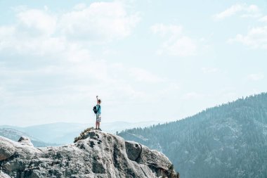 Yosemite Milli Parkı yarım kubbe cliff ters sitesindeki hayran uçurumun kenarına çok üzerinde duran genç adam.