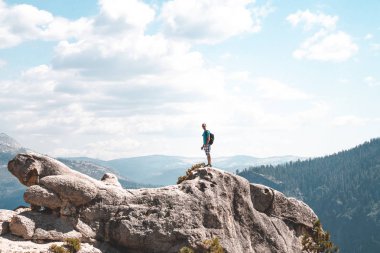 Yosemite Milli Parkı yarım kubbe cliff ters sitesindeki hayran uçurumun kenarına çok üzerinde duran genç adam.