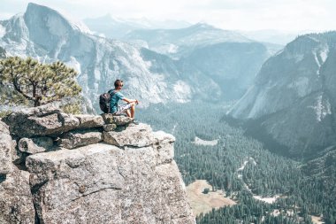 Yosemite Milli Parkı yarım kubbe cliff ters sitesindeki hayran uçurumun kenarına çok üzerinde duran genç adam.