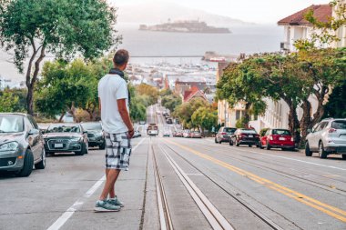 10 Eylül 2018. San Francisco, Amerika Birleşik Devletleri. Geleneksel teleferik ve arka planda Alcatraz Adası yakınında keşfetmek San Francisco genç adam.