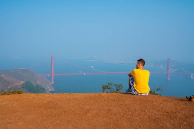 San Francisco Golden Gate Köprüsü manzaralı tepeler üzerine yürüyen genç adam. California keşfetmek.