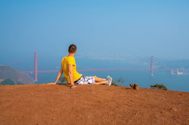 San Francisco Golden Gate Köprüsü manzaralı tepeler üzerine yürüyen genç adam. California keşfetmek.
