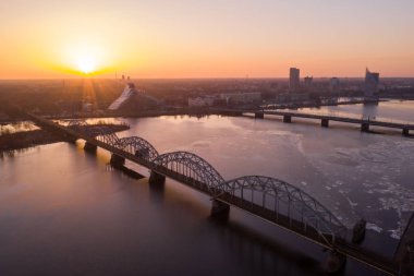 Riga, Letonya'da Gün Batımı sırasında Daugava Nehri üzerindeki Demiryolu Köprüsü'nün görünümü