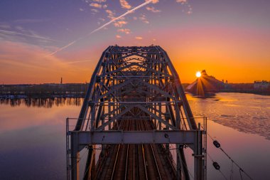 Riga, Letonya'da Gün Batımı sırasında Daugava Nehri üzerindeki Demiryolu Köprüsü'nün görünümü