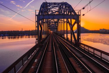 Riga, Letonya'da Gün Batımı sırasında Daugava Nehri üzerindeki Demiryolu Köprüsü'nün görünümü