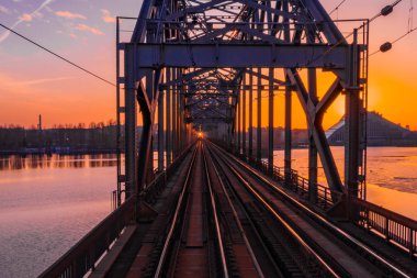 Riga, Letonya'da Gün Batımı sırasında Daugava Nehri üzerindeki Demiryolu Köprüsü'nün görünümü