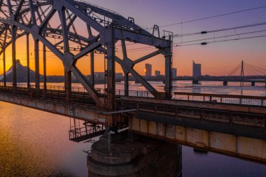 Riga, Letonya'da Gün Batımı sırasında Daugava Nehri üzerindeki Demiryolu Köprüsü'nün görünümü