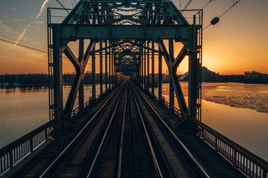 Riga, Letonya'da Gün Batımı sırasında Daugava Nehri üzerindeki Demiryolu Köprüsü'nün görünümü 