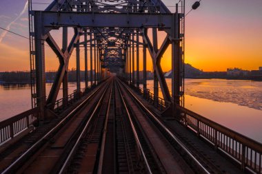 Riga, Letonya'da Gün Batımı sırasında Daugava Nehri üzerindeki Demiryolu Köprüsü'nün görünümü