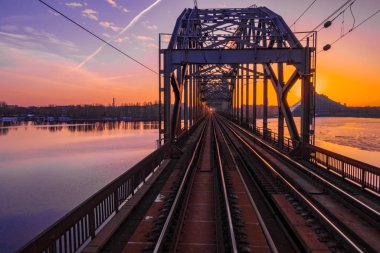 Riga, Letonya'da Gün Batımı sırasında Daugava Nehri üzerindeki Demiryolu Köprüsü'nün görünümü