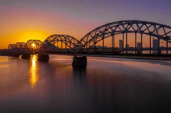 Riga, Letonya'da Gün Batımı sırasında Daugava Nehri üzerindeki Demiryolu Köprüsü'nün görünümü 