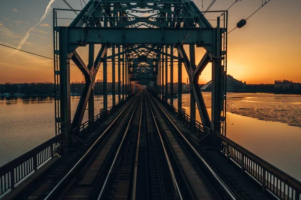 Riga, Letonya'da Gün Batımı sırasında Daugava Nehri üzerindeki Demiryolu Köprüsü'nün görünümü 