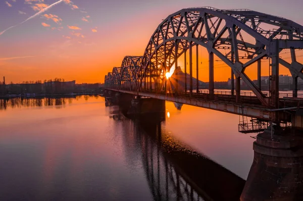 Riga, Letonya'da Gün Batımı sırasında Daugava Nehri üzerindeki Demiryolu Köprüsü'nün görünümü