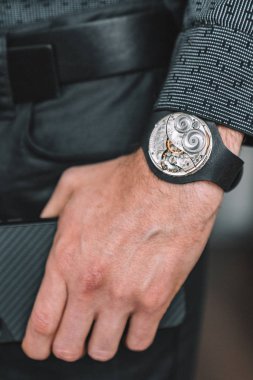 Young businessman holding his hand in the pocket with a classical skeleton watch on his hand.