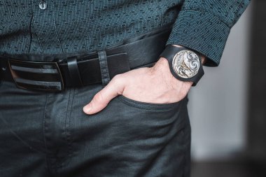 Young businessman holding his hand in the pocket with a classical skeleton watch on his hand.