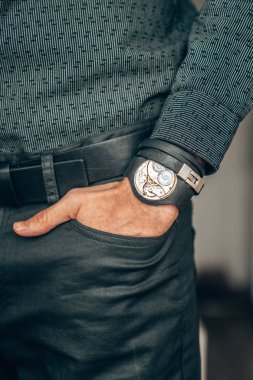 Young businessman holding his hand in the pocket with a classical skeleton watch on his hand.