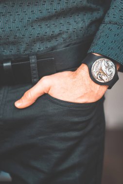 Young businessman holding his hand in the pocket with a classical skeleton watch on his hand.