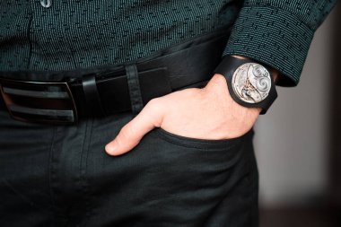 Young businessman holding his hand in the pocket with a classical skeleton watch on his hand.