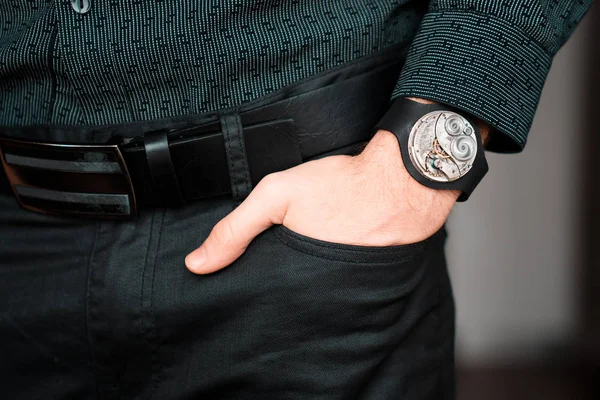 Young businessman holding his hand in the pocket with a classical skeleton watch on his hand.
