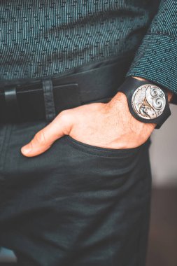 Young businessman holding his hand in the pocket with a classical skeleton watch on his hand.