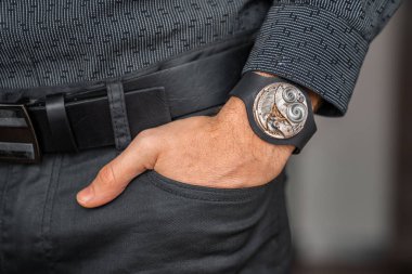 Young businessman holding his hand in the pocket with a classical skeleton watch on his hand.
