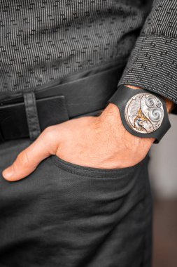 Young businessman holding his hand in the pocket with a classical skeleton watch on his hand.