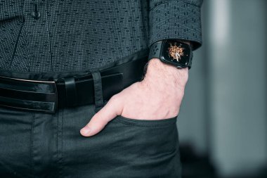 Young businessman wearing a smart watch, holding his hand in a pocket.