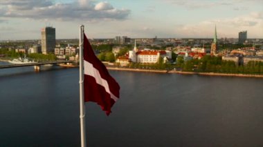 Arka planda bir Riga şehri ile rüzgarda sallanan Letonya bayrağı.