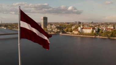 Arka planda bir Riga şehri ile rüzgarda sallanan Letonya bayrağı.