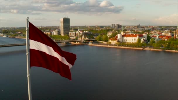リガの街を背景に風に揺るぐラトビアの旗 — ストック動画